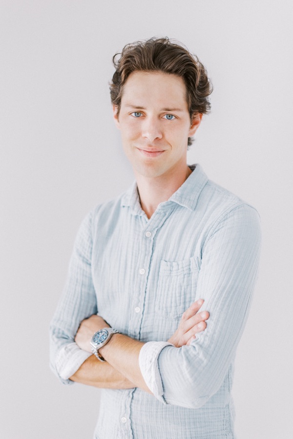 Blake in a casual shirt, standing with his arms folded.